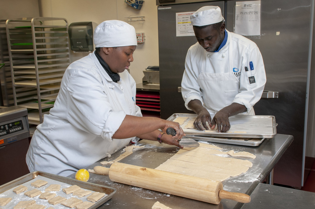 Student chefs prepare food in the kitchen as customers wait to file into The Red Room.