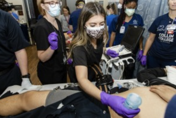 A diagnostic medical sonography student prepares to examine an actor playing a trauma patient.