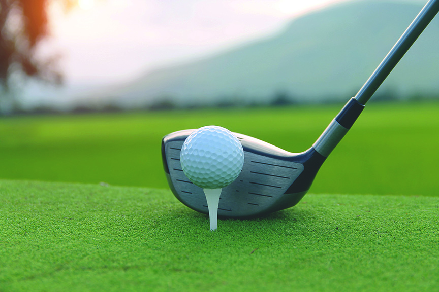 An image of a driver golf club behind a golf ball